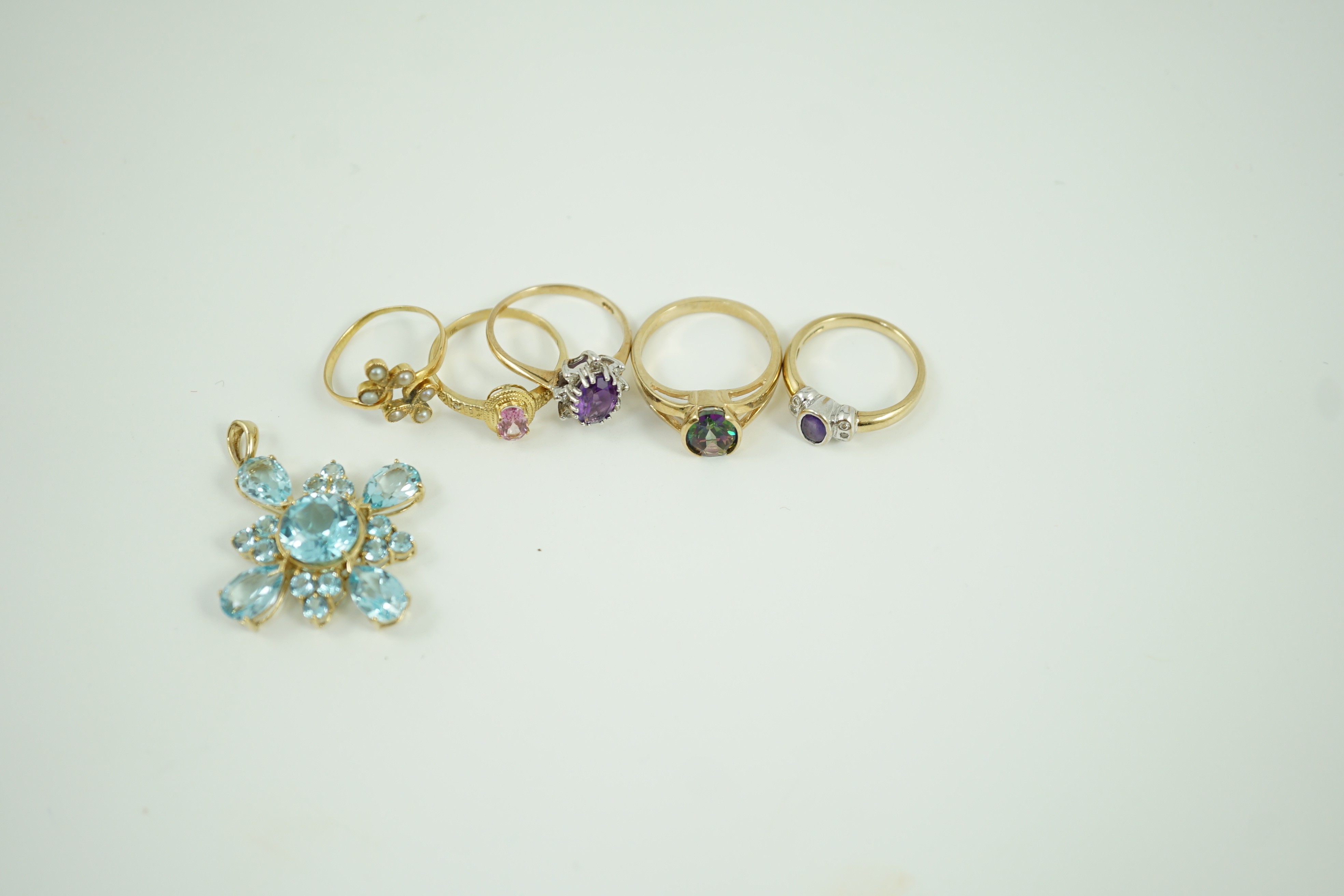 Four assorted modern 9ct gold and gem set rings, a white metal and seed pearl ring and a 9ct gold and blue stone cluster set pendant, 33mm, gross weight 17.9 grams.